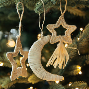 Decorative moon and star ornaments hanging on a Christmas tree.