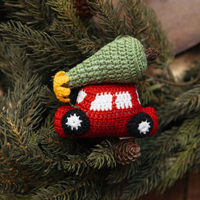 Crocheted red car ornament with a green tree on a Christmas tree.