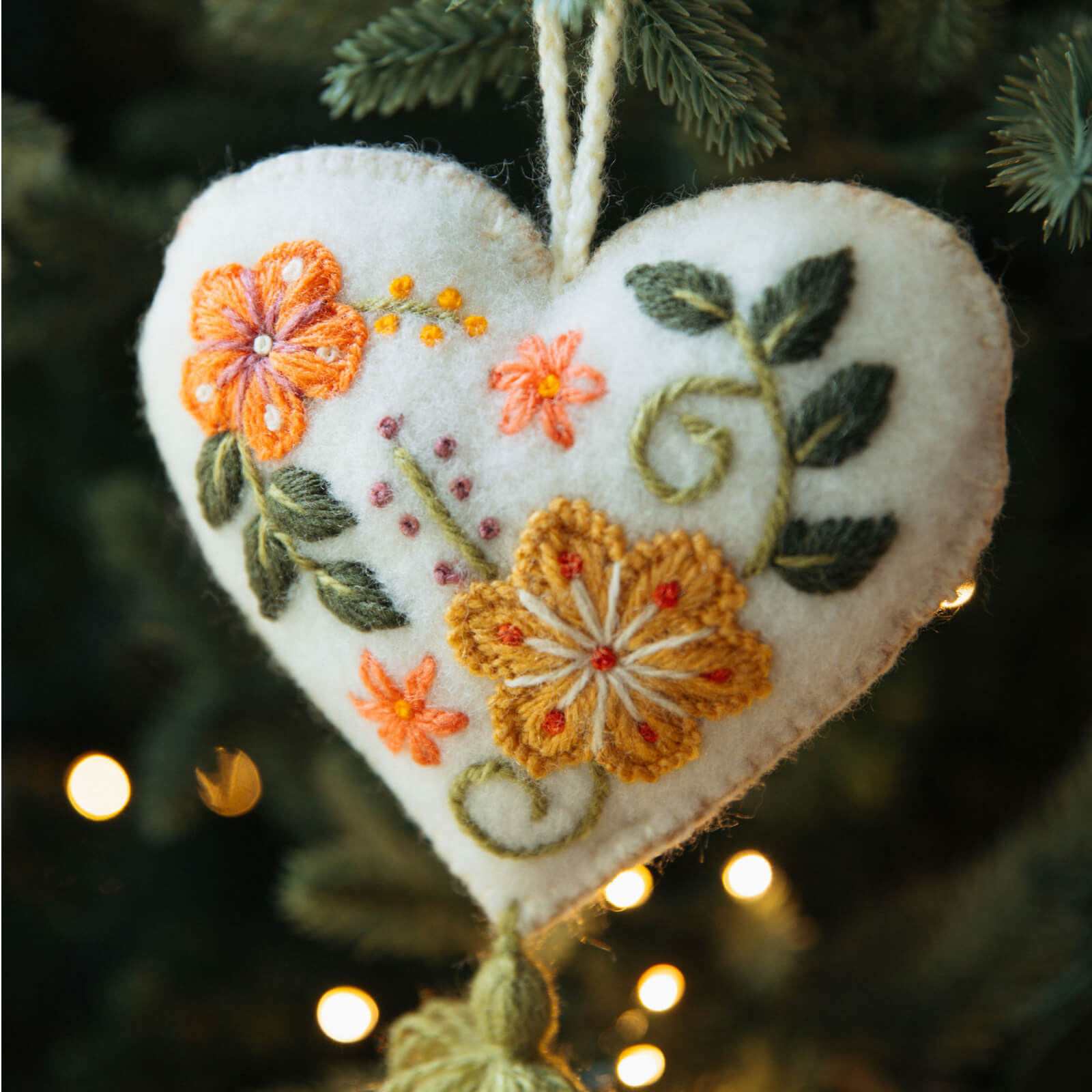 Heart-shaped embroidered ornament with flowers on a Christmas tree.