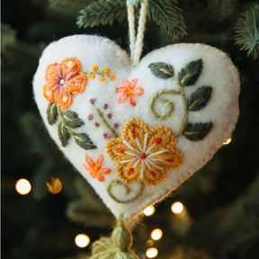 Heart-shaped embroidered ornament with flowers on a Christmas tree.