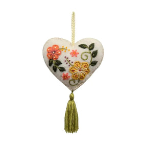 Heart-shaped embroidered ornament with flowers and a tassel on a white background