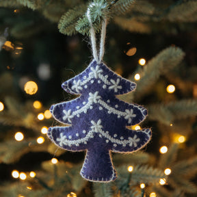 Decorative purple tree ornament on a Christmas tree with blurred lights in the background