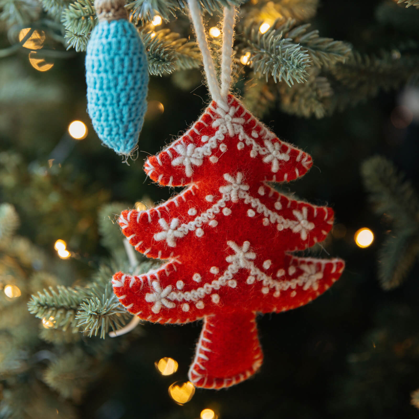 Red Christmas tree ornament with white snowflakes on a decorated tree
