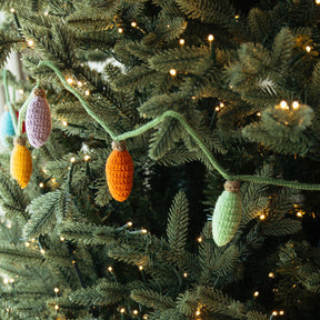 Decorative crochet ornaments on a Christmas tree with lights.