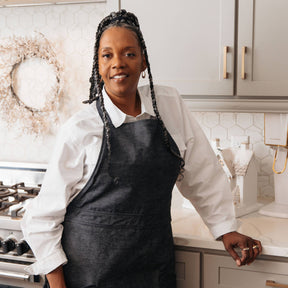 Person wearing a black apron in a kitchen setting