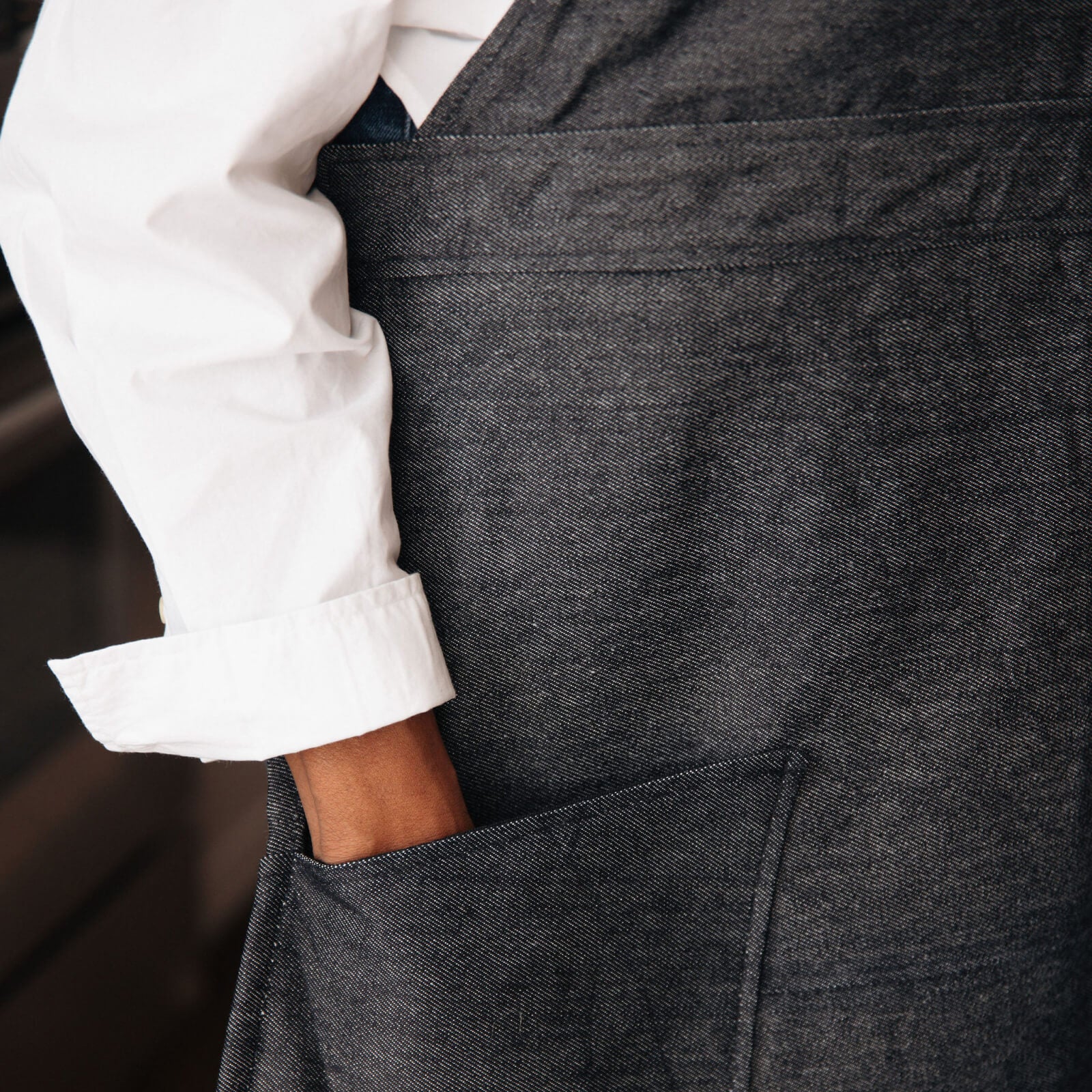 Close-up of a person wearing a dark gray apron over a white shirt.