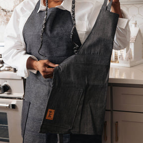 Person wearing a dark denim apron in a kitchen setting
