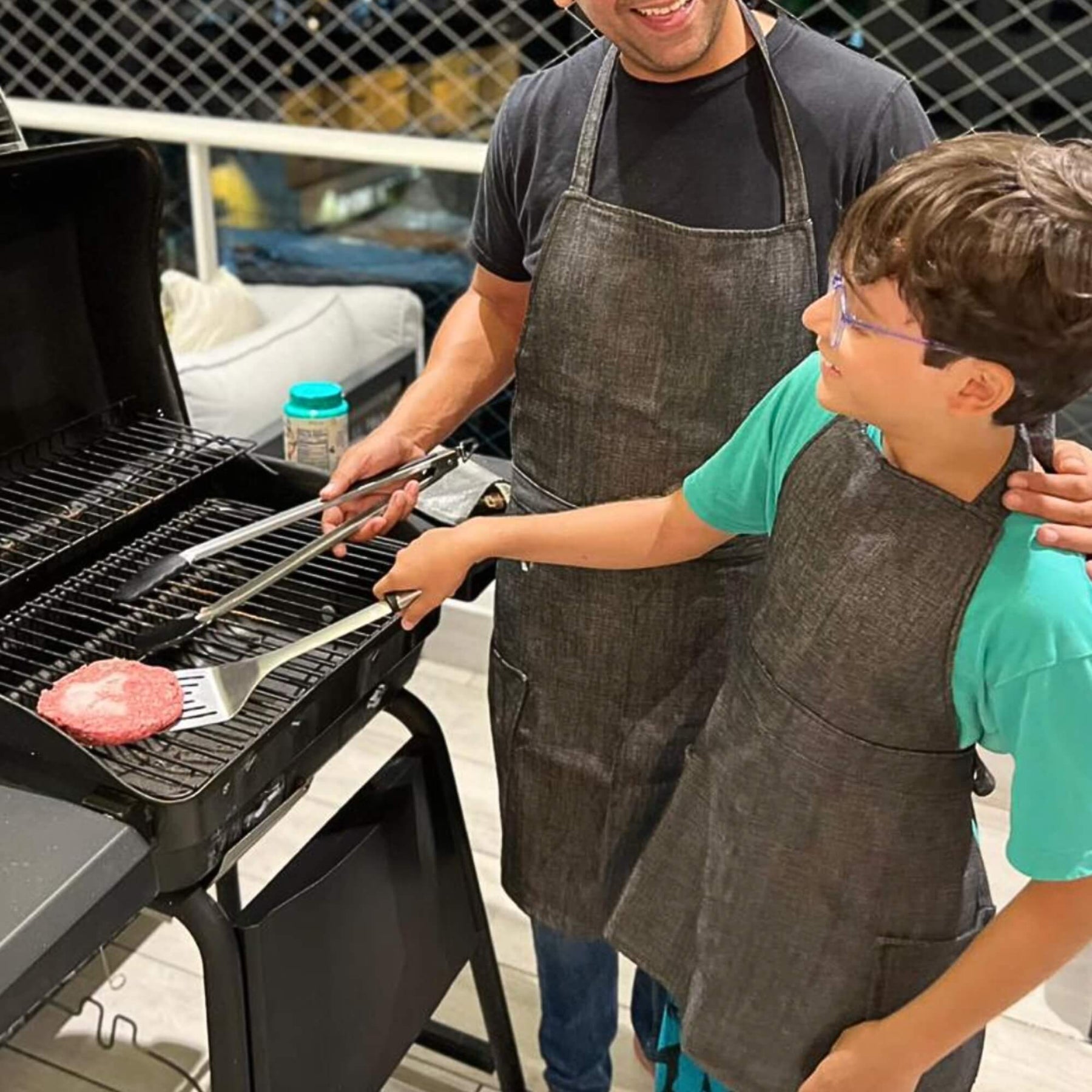 Man and child grilling together with aprons on