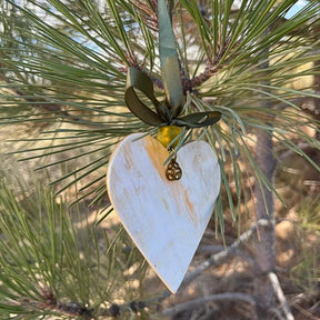 Heart-shaped ornament hanging from a pine branch