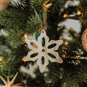 Decorative snowflake ornament on a Christmas tree with blurred lights in the background