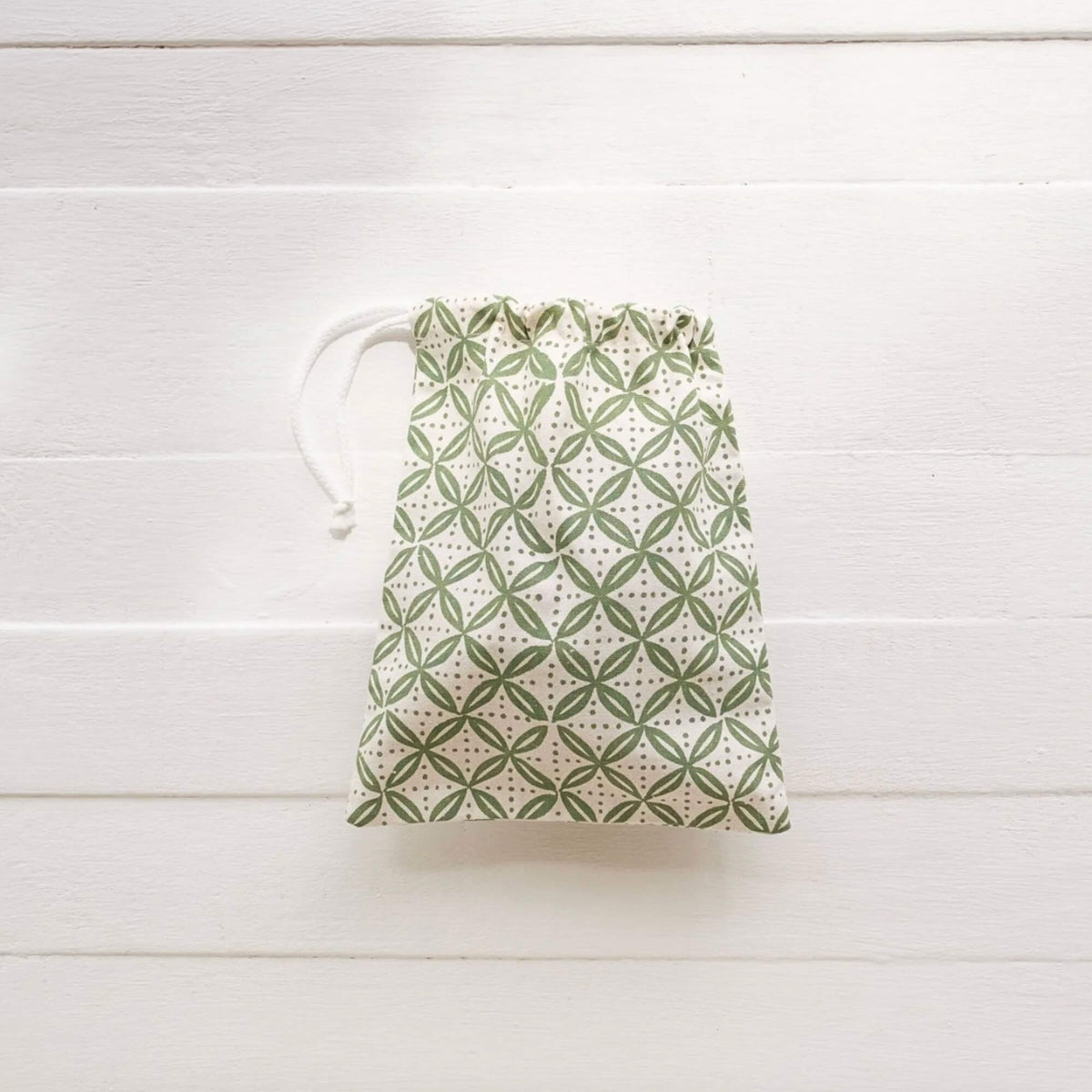 Drawstring bag with green geometric pattern on a white wooden surface