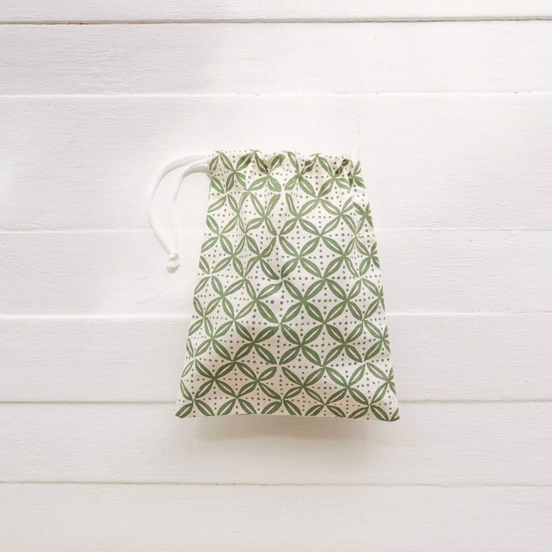 Drawstring bag with green geometric pattern on a white wooden surface