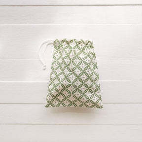 Drawstring bag with green geometric pattern on a white wooden surface