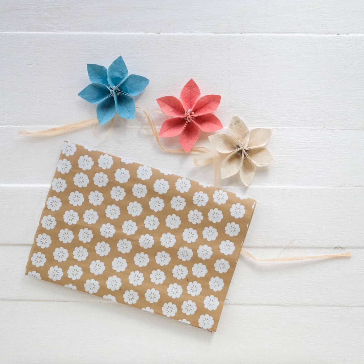 Floral ornaments and a floral-patterned paper on a white wooden surface