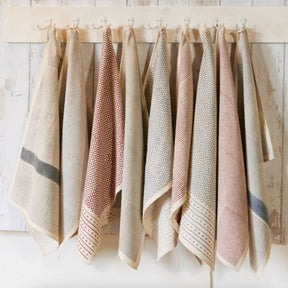 Set of patterned towels hanging on a wooden rack against a light wooden wall.