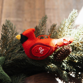 Red cardinal bird ornament on a branch with pine cones and greenery