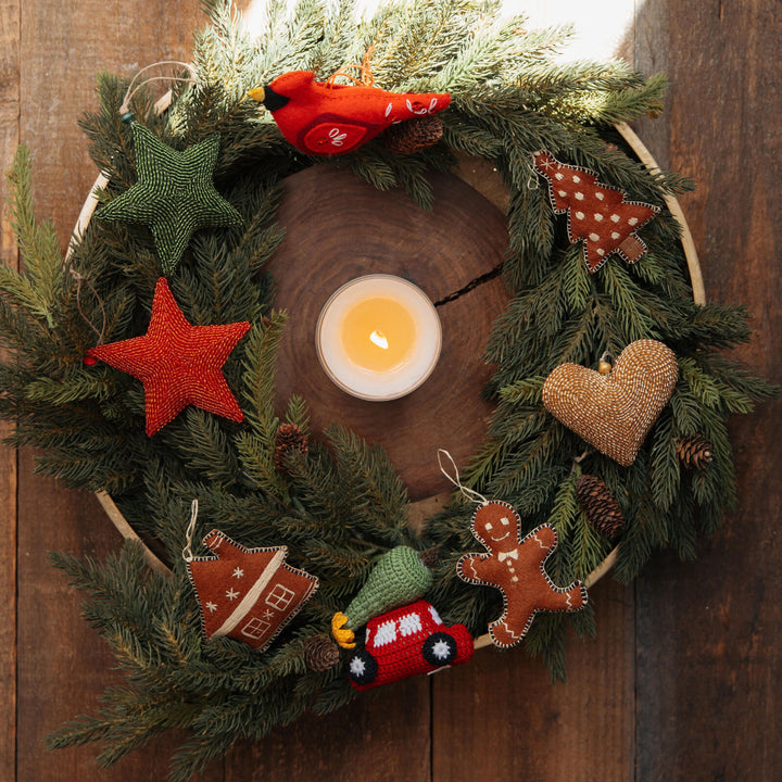Decorative Christmas wreath with candles, stars, and small figurines on a wooden background