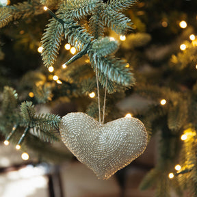 Heart-shaped ornament on a decorated Christmas tree with lights.