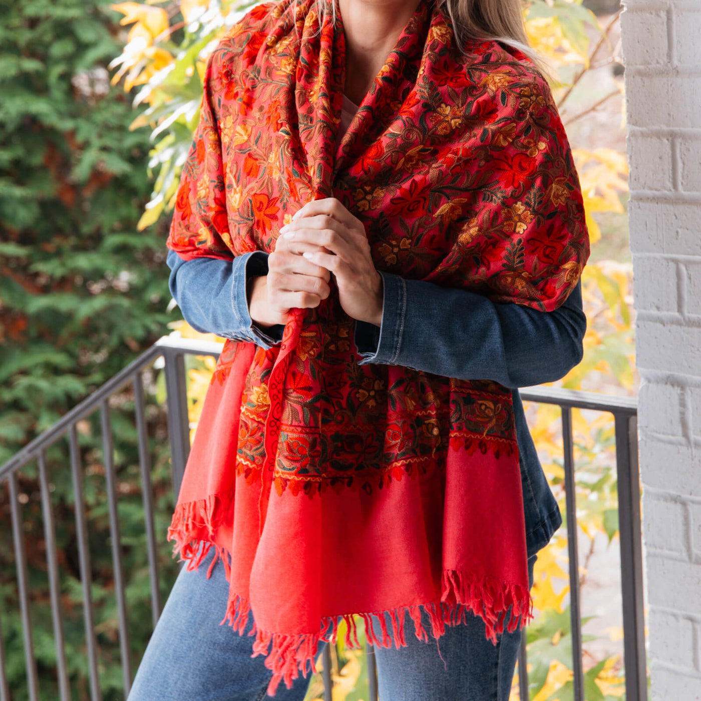 Person wrapped in a red embroidered shawl with intricate patterns.