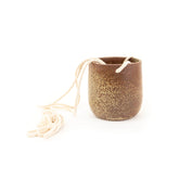Ceramic planter with speckled glaze and string on a white background