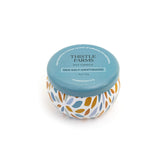 Candle jar with floral design and blue lid labeled 'Thistle Farms' on a white background