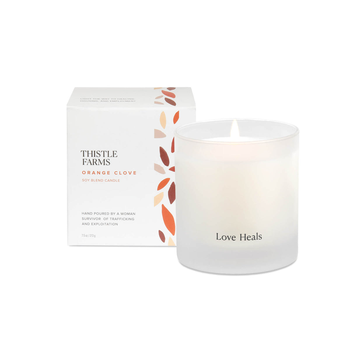 Frosted Glass Candle with Love Heals script printed on outside tumbler. Box is placed behind the candle with orange and brown petals.