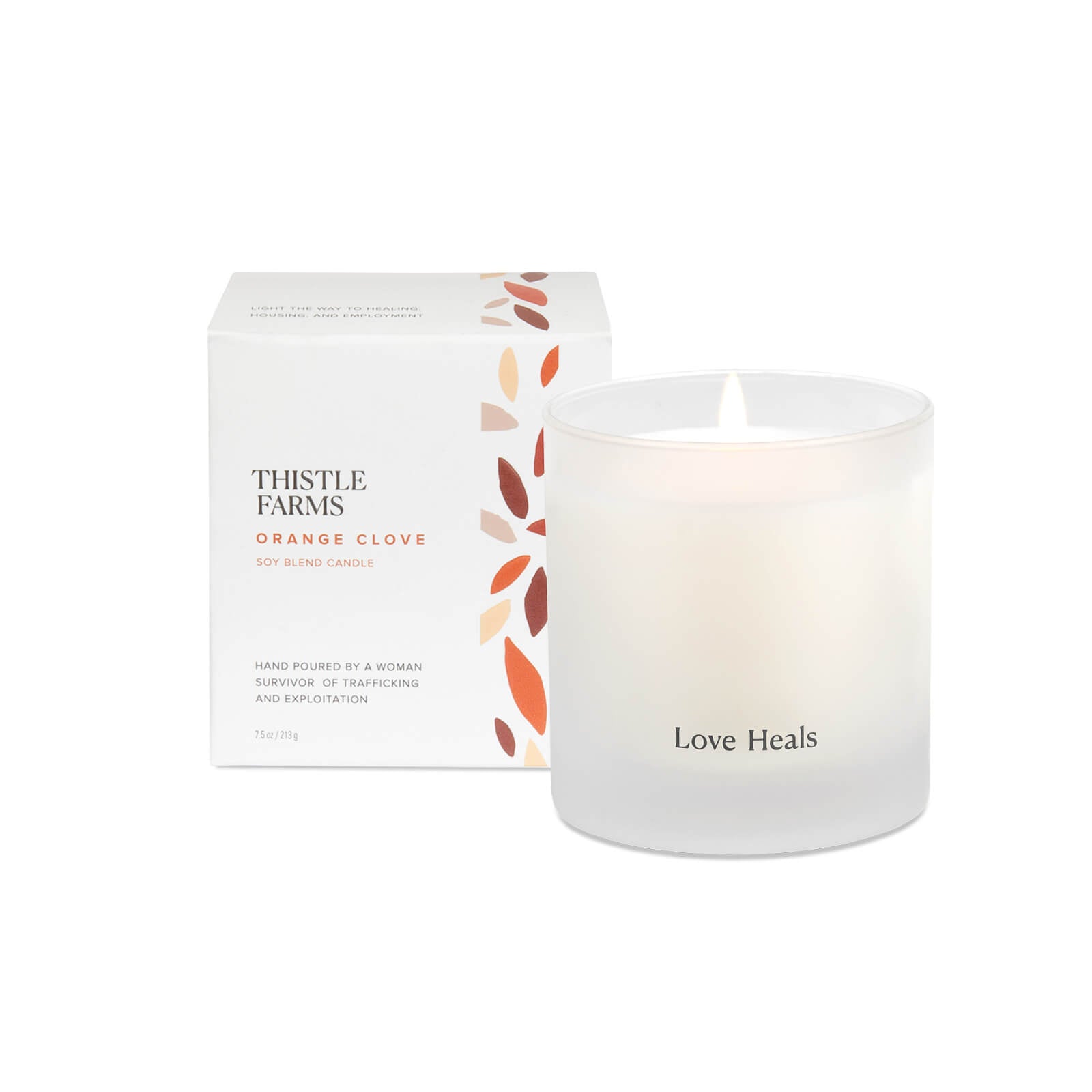 Frosted Glass Candle with Love Heals script printed on outside tumbler. Box is placed behind the candle with orange and brown petals.
