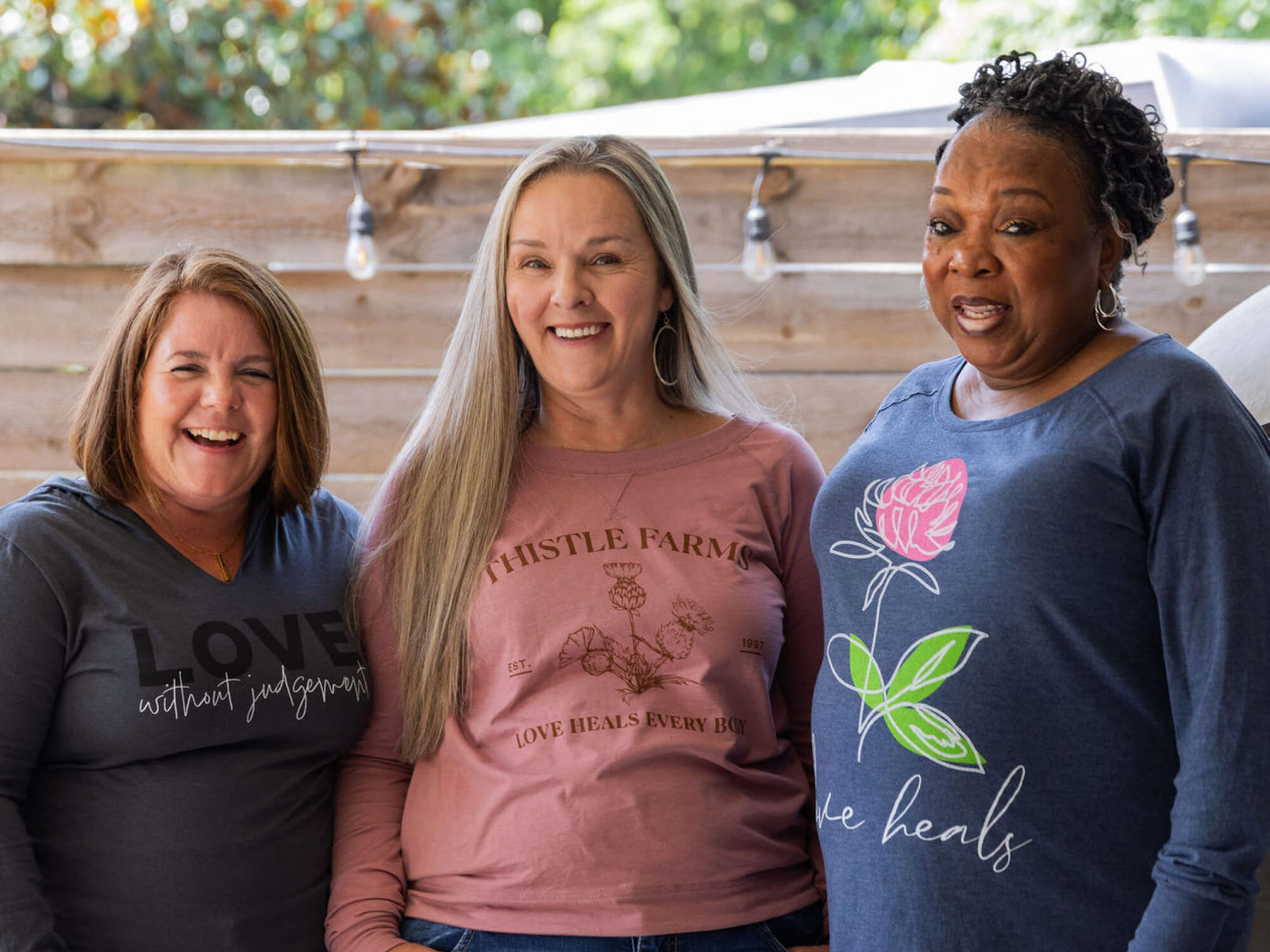 Three women wearing shirts with motivational phrases outdoors