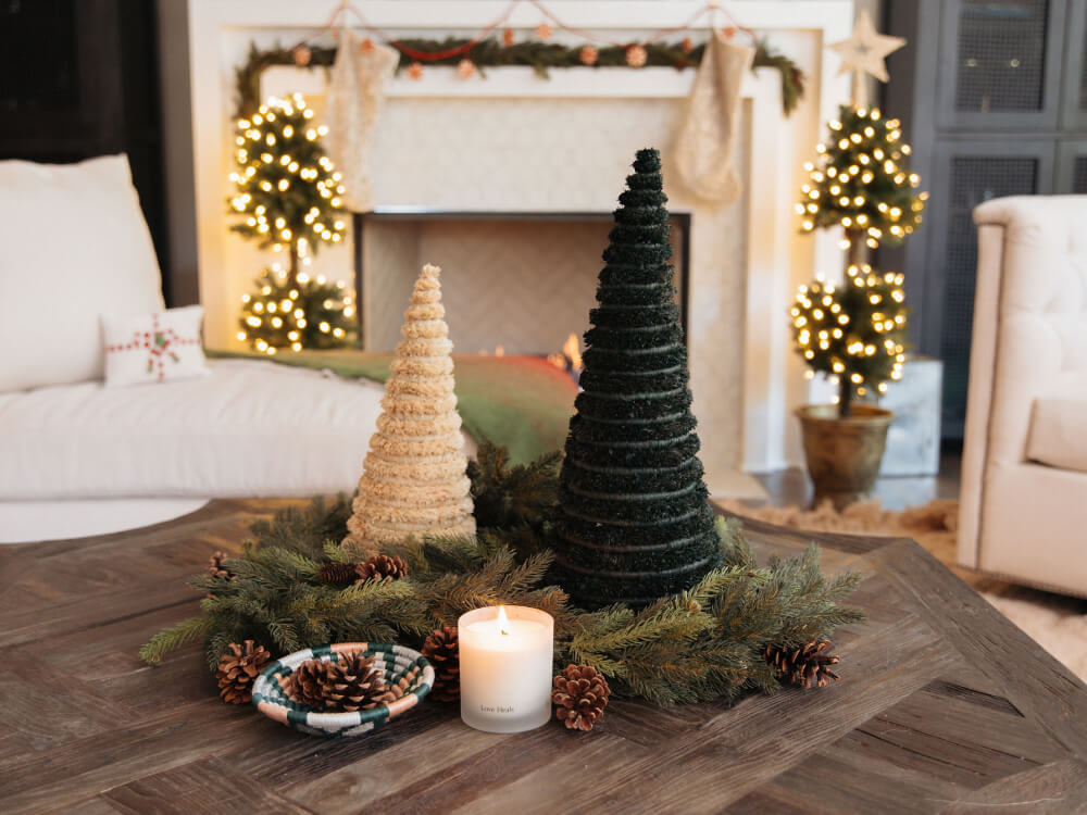 Decorative Christmas trees and candles on a coffee table with a festive living room background.