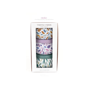 Three patterned cups in a box with 'Thistle Farms' branding on a white background