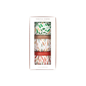 Three patterned candles in a box with 'Thistle Farms' branding on a white background.