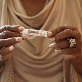 Person holding a lip balm stick with a neutral background
