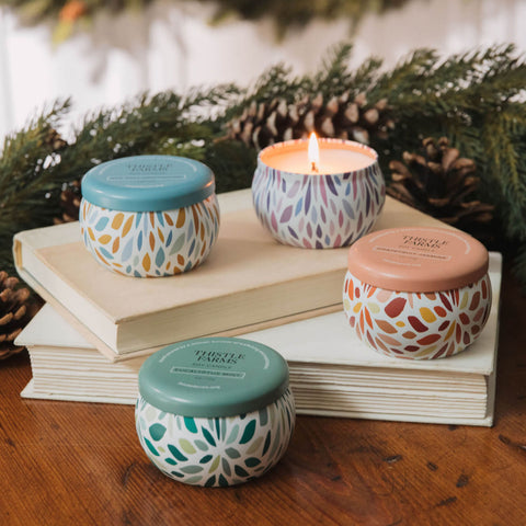Four patterned candles on books with a festive blurred natural background