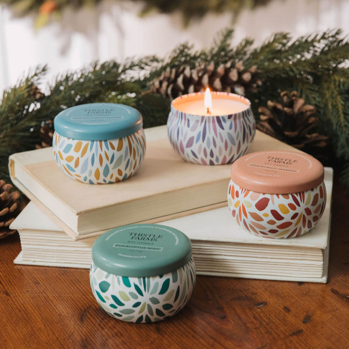 Four patterned candles on books with a festive blurred natural background