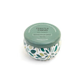 Thistle Farms soy candle with green lid and leaf patterned base on a white background