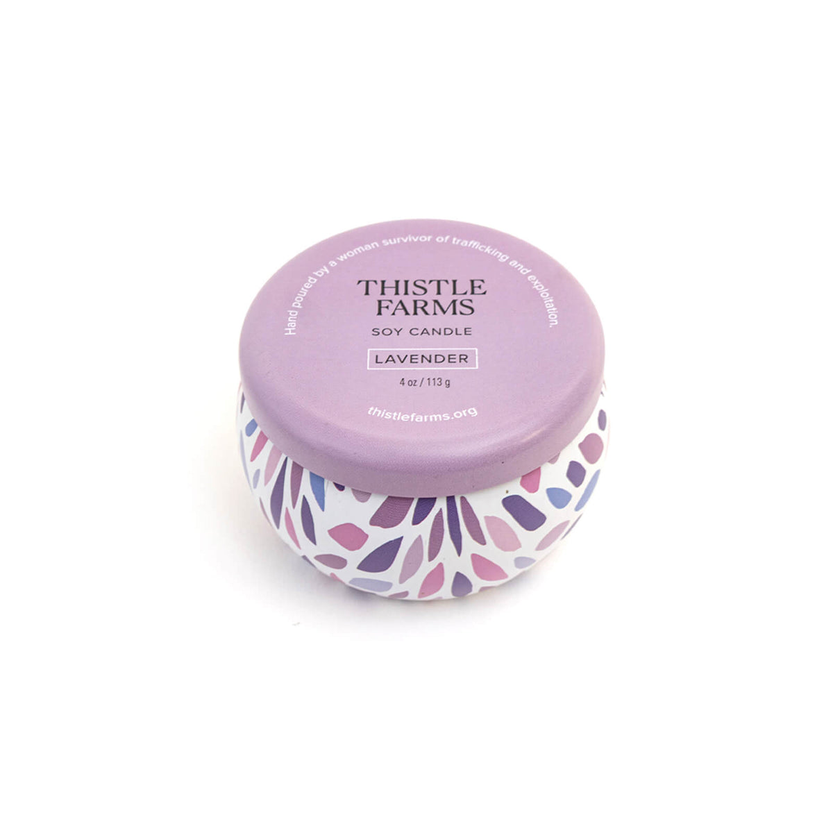 Thistle Farms soy candle with purple lid and leaf patterned base on a white background