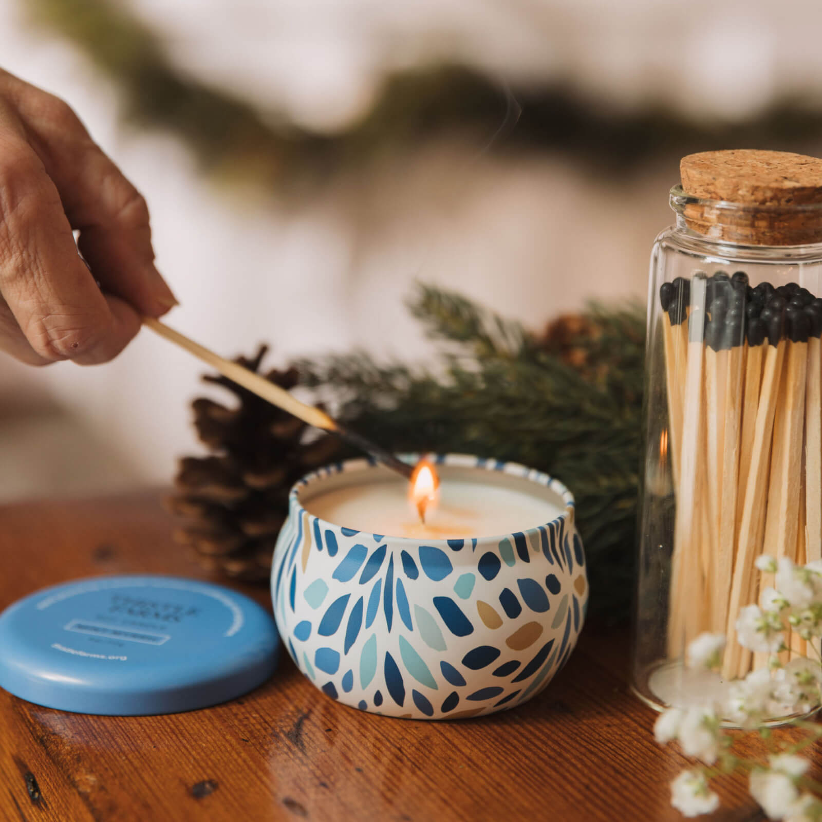 Candle being lit with a match, surrounded by decorative elements on a wooden surface.