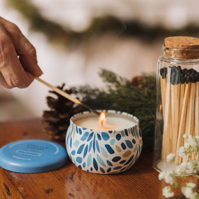 Candle being lit with a match, surrounded by decorative elements on a wooden surface.