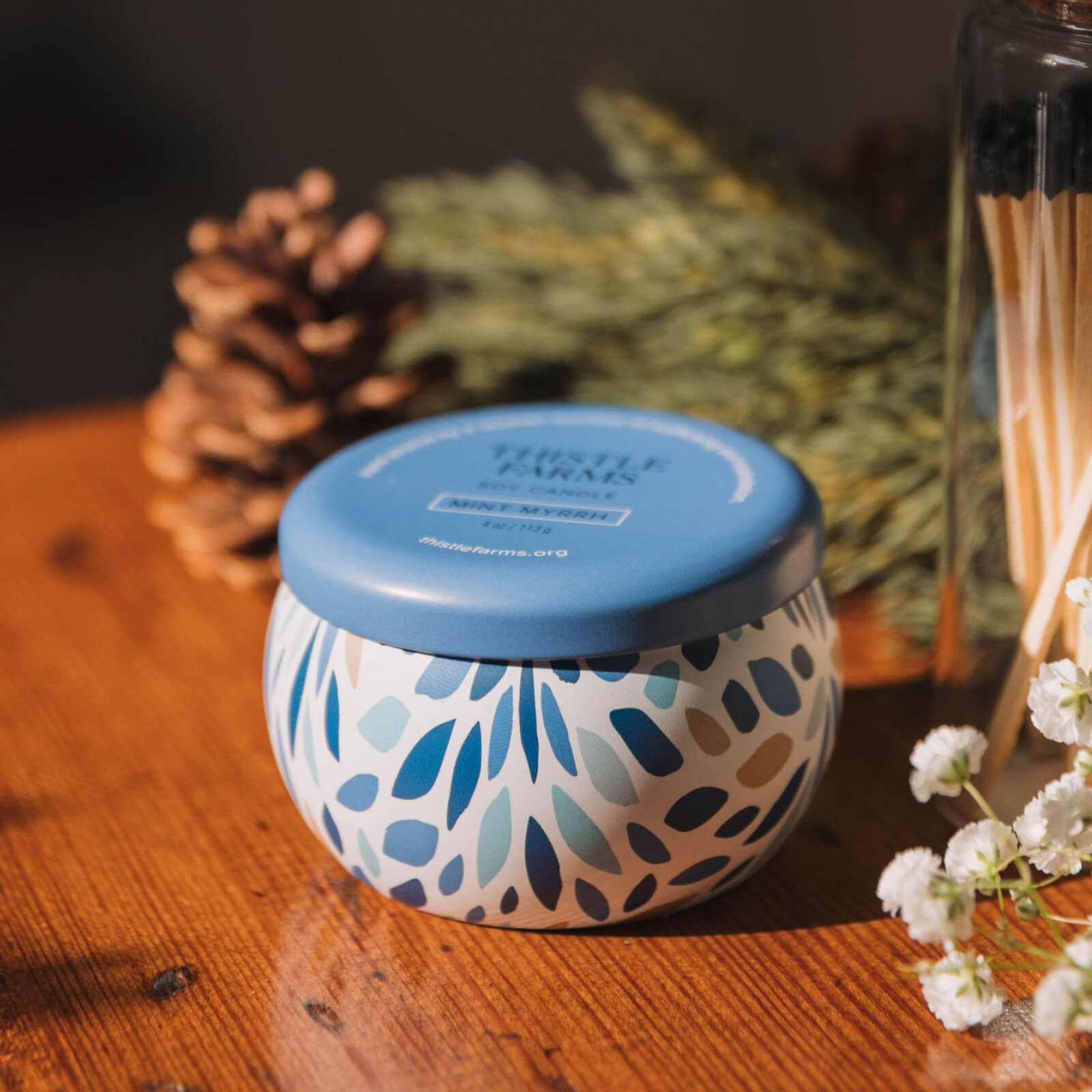 Candle jar with blue lid on a wooden surface with decorative elements