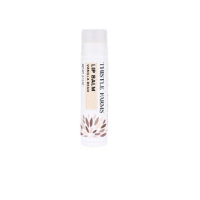 A single tube of Thistle Farms Lip Balm in Vanilla Bean scent, shown against a plain white background. The tube is white with black text and a small brown leaf pattern near the bottom.