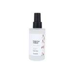 A frosted glass spray bottle of Thistle Farms Vanilla Bean Hydration Mist with a black spray nozzle and a white label featuring botanical leaf illustrations.