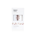 Thistle Farms Love Heals Vanilla Bean Hand Soap & Hand Lotion set in a white rectangular box with a clear window showing the white soaps inside, on a white background.