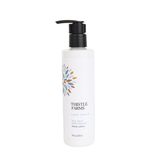 A bottle of Thistle Farms Love Heal Sea Salt Dampwood Hand Lotion with a black pump dispenser and a white label featuring a blue and orange leaf design, set against a plain white background.