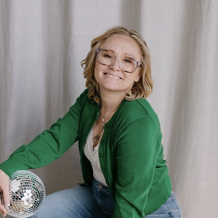 woman wearing a green top holding a disco ball 